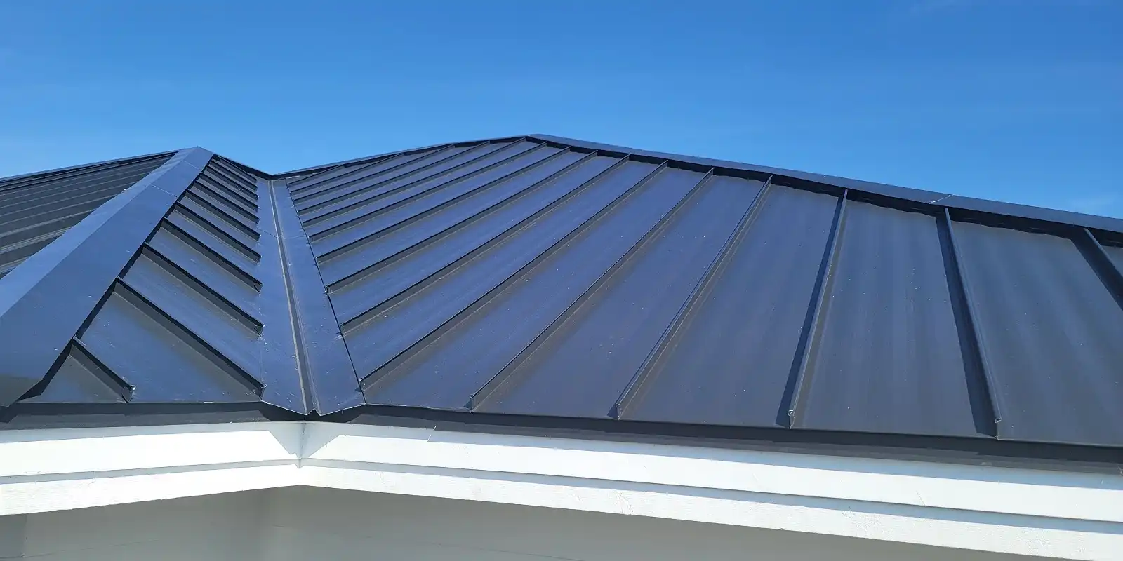 Planet Roofing metal crew trimming drip edges on a finished aluminum roof in Fort Lauderdale