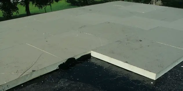Roofer hot-mopping insulation boards over a concrete roof deck