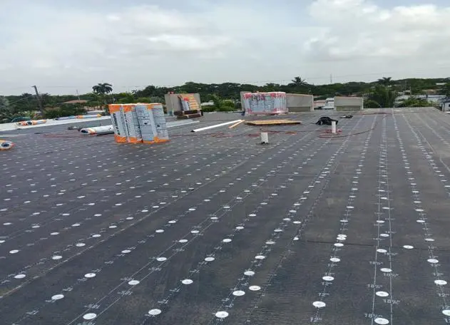 Tin tag installation in progress on a commercial roof, demonstrating quality control or identification efforts.