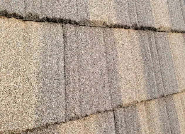 Stone-coated steel roof on a mansard-style building with a flat roof and lighter color finish