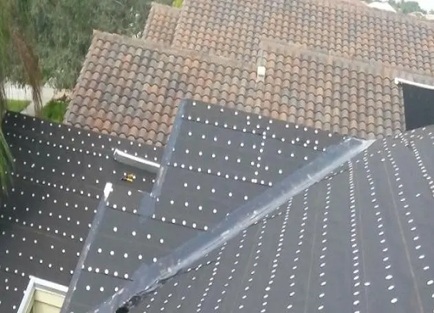 Tiny tag being installed on a tile roof, likely for identification or quality control purposes.