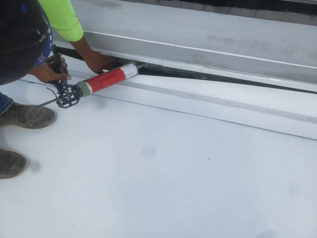 Roofer applying sealant to roof flashing in Fort Lauderdale